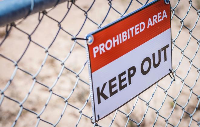 Sign on Chain Link Fence that Says Prohibited Area, Keep Out